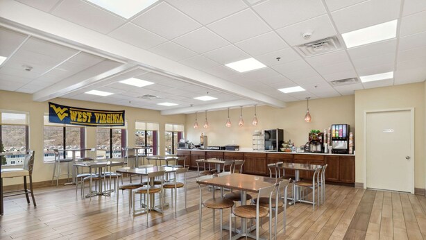 A spacious dining area with multiple tables and chairs, a kitchen area with a counter, and a large banner reading "West Virginia".