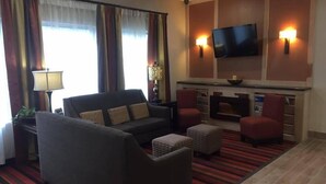 A hotel room with a sofa, two armchairs, a flat-screen TV, and a fireplace.