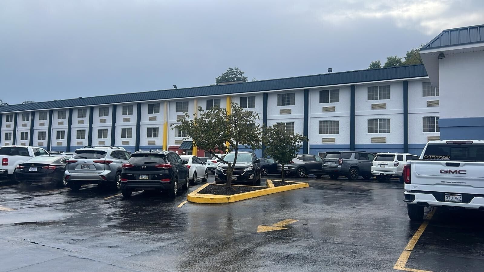 A parking lot with multiple cars and a building with a blue and white facade.