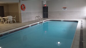 An indoor swimming pool with a lifebuoy, a lifeguard chair, and a poolside table.