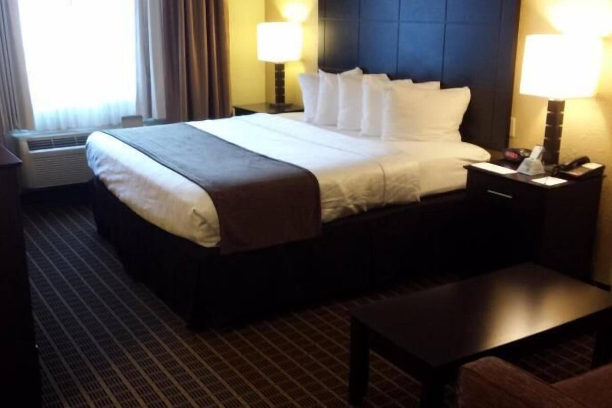 A hotel room with a bed, bedside tables, a desk, and a chair.