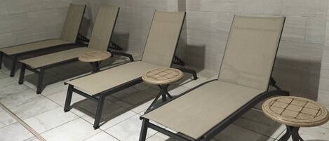 Cuatro sillones de descanso con asientos y respaldos acolchados, alineados frente a una pared de azulejos.