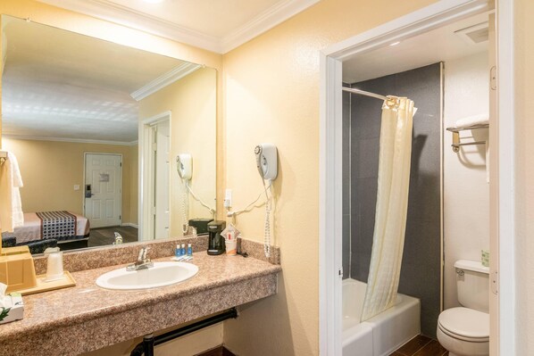 A bathroom with a sink, mirror, shower, and toilet.
