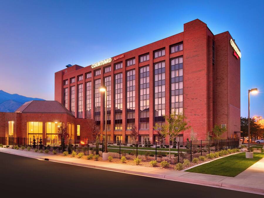 Un hotel Courtyard Marriott con fachada de ladrillo, ventanas amplias y una entrada bien iluminada.
