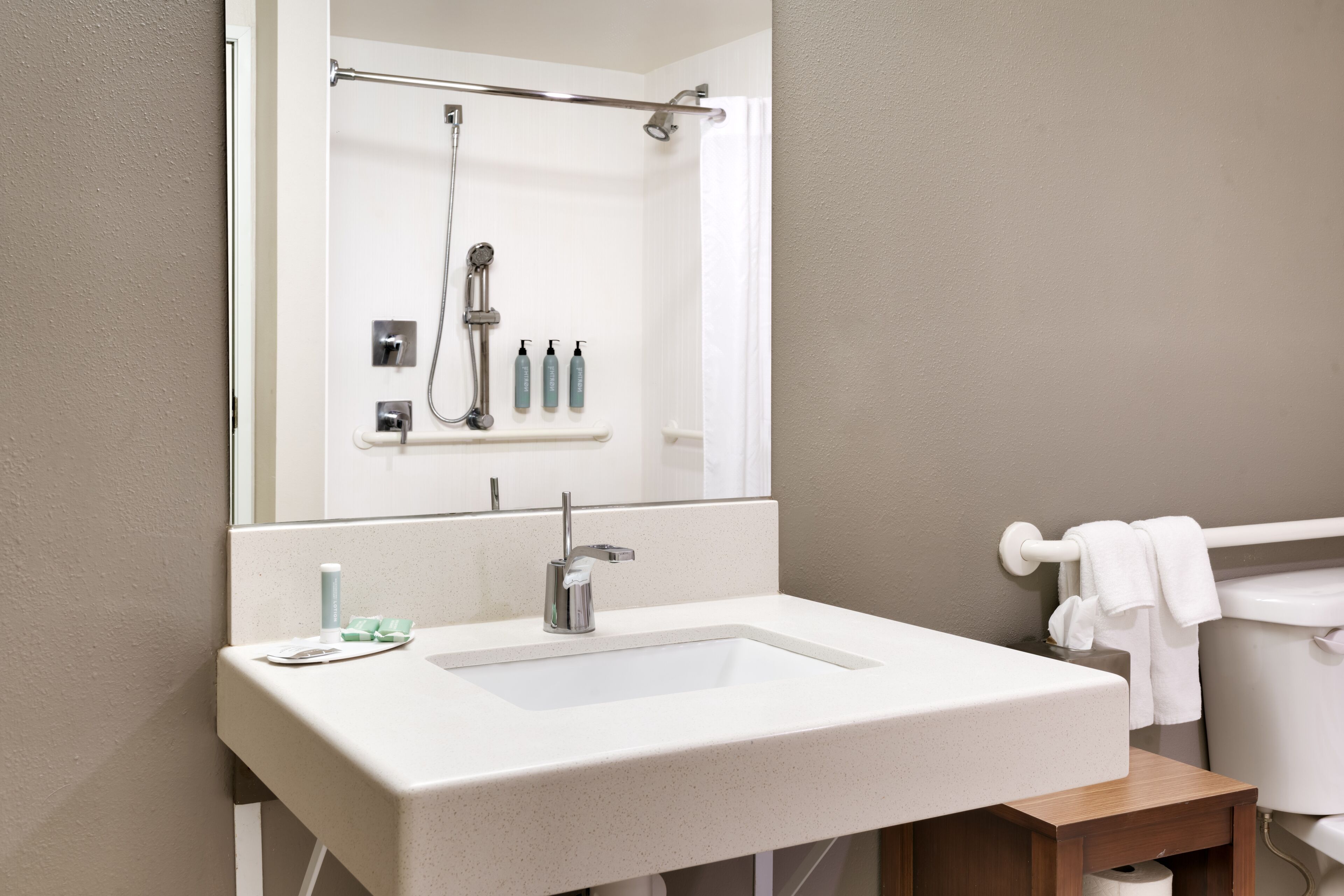 Un baño con lavamanos blanco, un espejo, ducha y retrete.