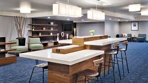 Una sala de conferencias moderna con una mesa grande, taburetes tipo bar y una zona de estar con sillas y un sofá.