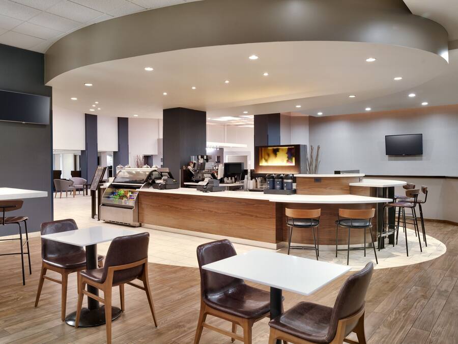 Un restaurante moderno con una barra curva, varias zonas de estar y una cocina al fondo.