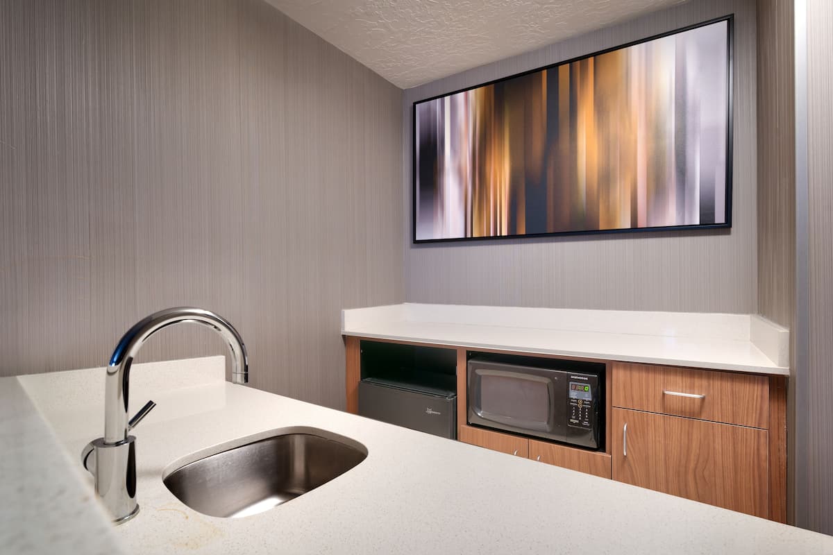 A modern kitchen with a stainless steel sink, a built-in microwave, and a wooden cabinet.