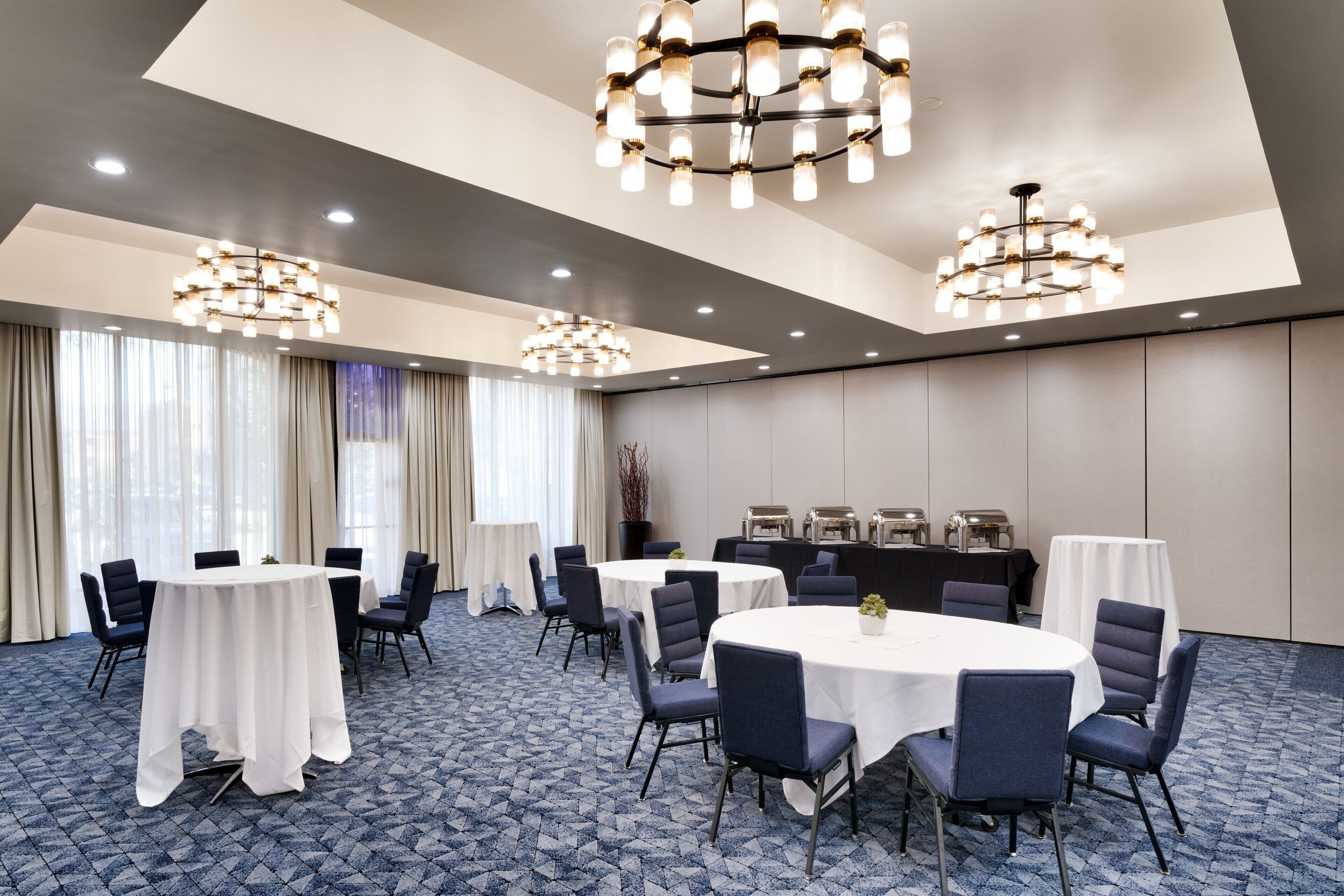Un salón de conferencias con mesas redondas, sillas y candelabros.