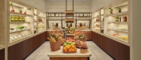 A spacious kitchen with marble countertops, wooden cabinets, and a central island with fresh produce.