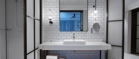 A modern bathroom with a white sink, a mirror, and a shower.