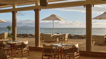 Enjoy meals with a scenic view of the ocean and distant mountains from this beachfront dining area.