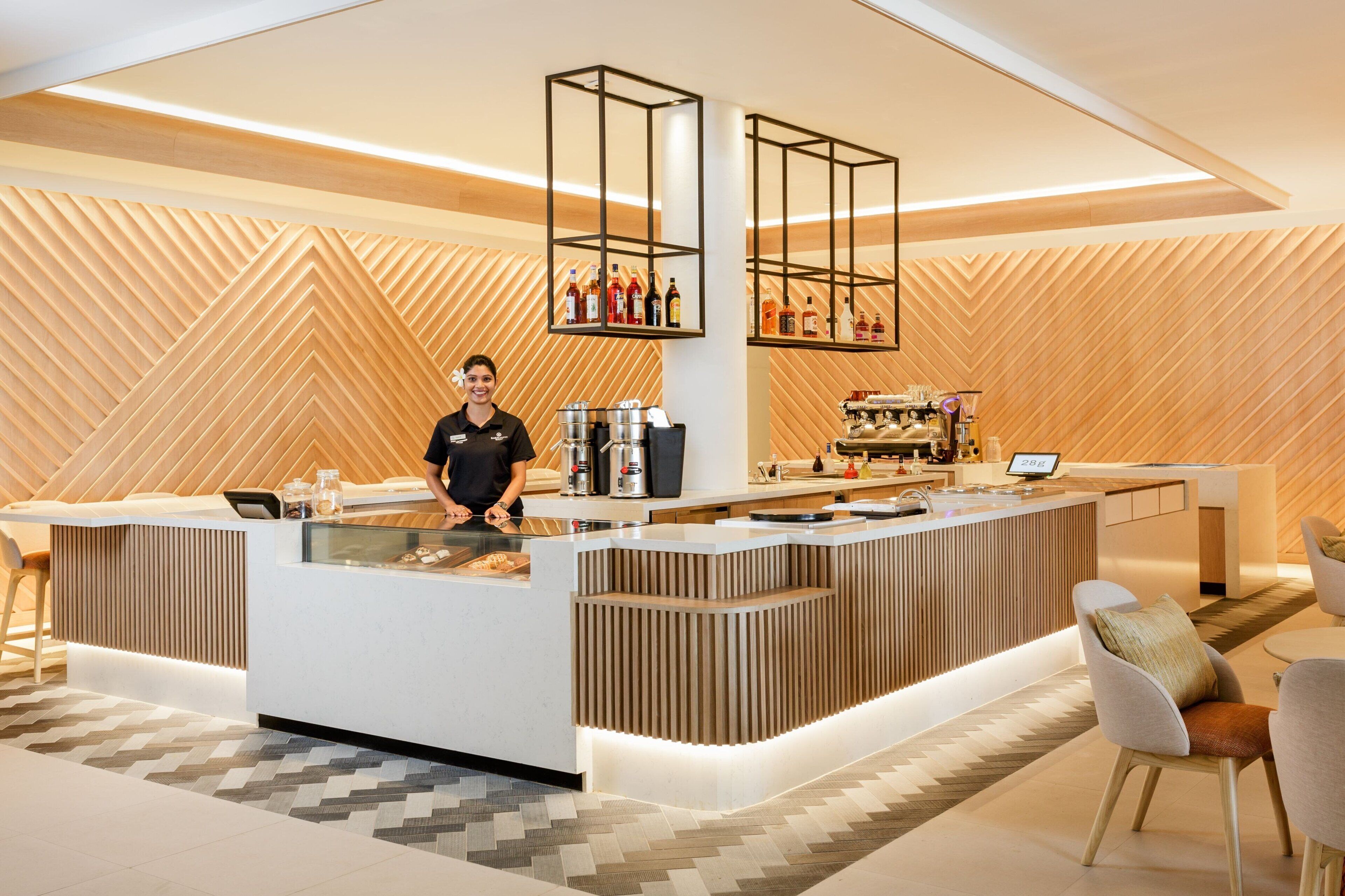 Un espace bar moderne avec un barista, une machine à café et un choix de boissons.
