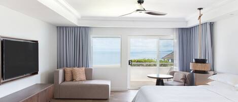 Una habitación de hotel con cama, sofá, televisor y balcón con vista al mar.