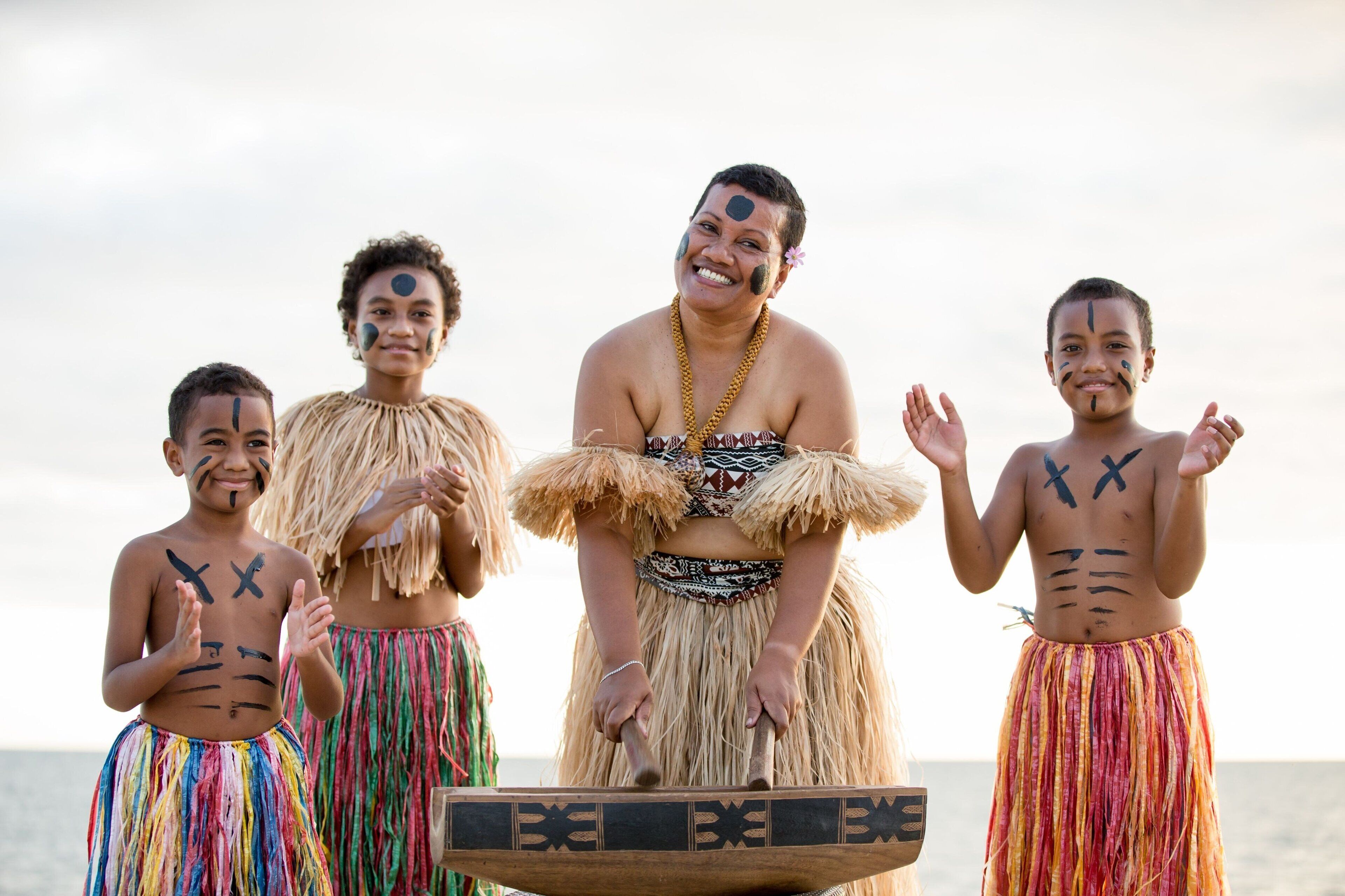 A group of people in traditional attire with a wooden boat in the foreground.