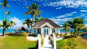 A beachside resort with a central pavilion, palm trees, and a clear view of the ocean. - Sheraton Fiji Golf & Beach Resort (Nadi)