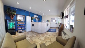 A reception area with a blue wall, a refrigerator, a vending machine, and a reception desk. - Americas Best Value Inn Williams Grand Canyon (Williams)