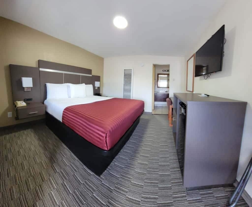 Ein Hotelzimmer mit Bett, Schreibtisch, Fernseher und einer Küchenzeile.