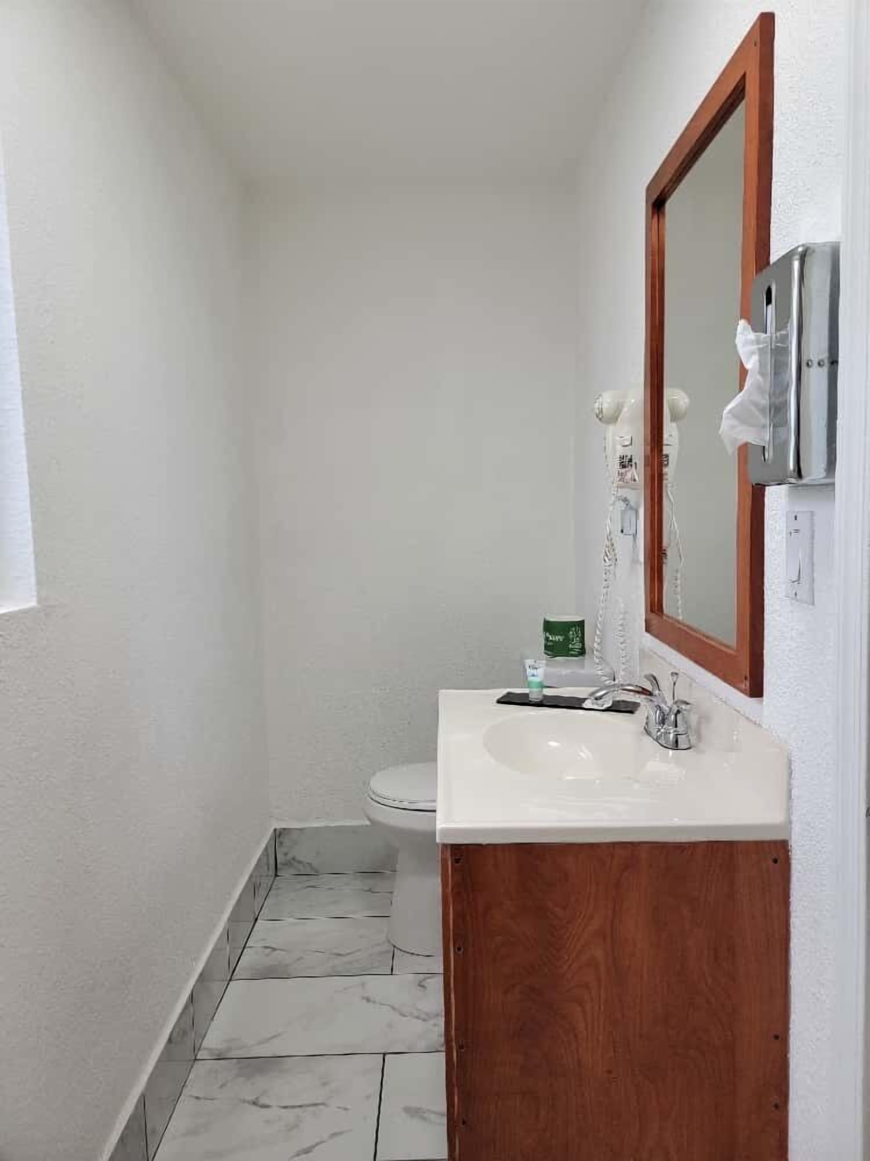 A small bathroom with a white sink, wooden vanity, and a mirror.
