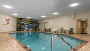 Una piscina interior con un mural de un puente, sillas de descanso y un cartel que indica 'NO DIVING'.