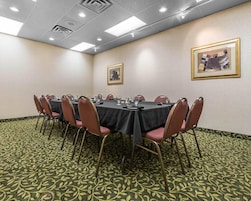 Un salón de conferencias con una larga mesa, sillas y cuadros en las paredes.
