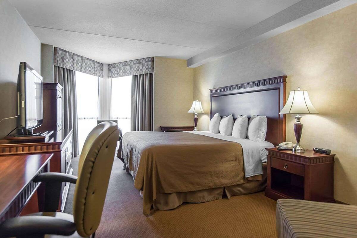 Une chambre d’hôtel avec un grand lit, un bureau avec une télévision, une chaise et une table de chevet avec une lampe.