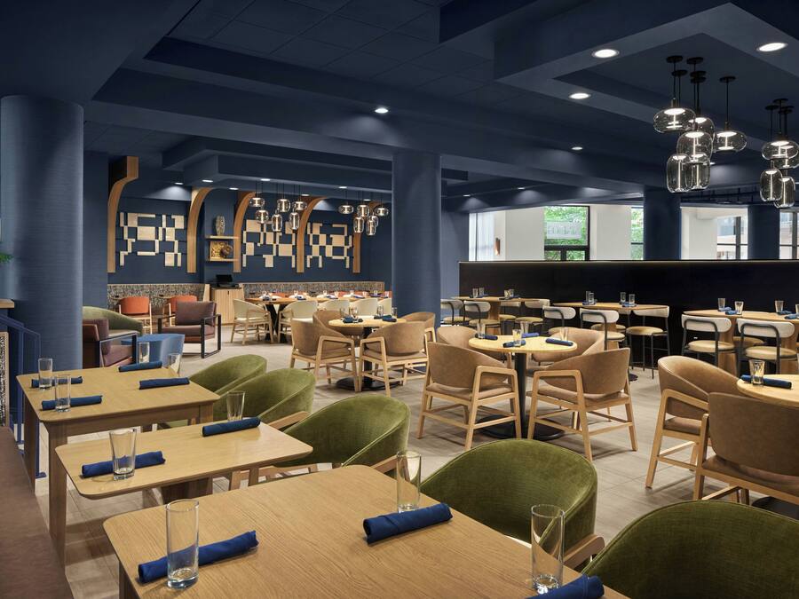 A modern restaurant interior with multiple dining tables and chairs, a bar area, and decorative wall art.