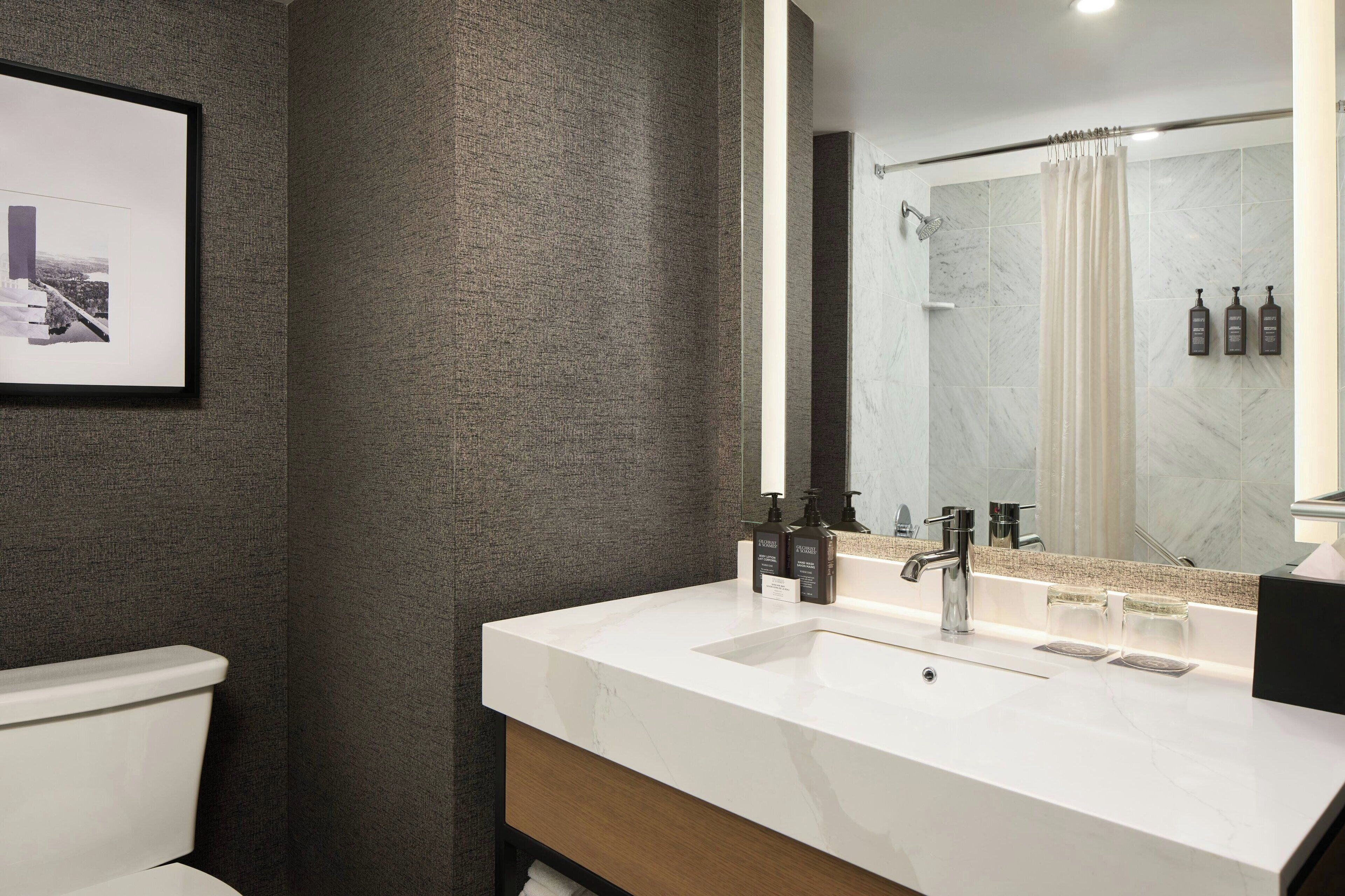 Une salle de bain moderne avec un grand miroir, un lavabo blanc et un espace douche.