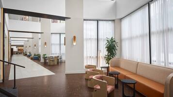 Un vestíbulo amplio con una zona de estar central, una escalera y vistas al comedor.