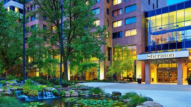 Een Sheraton hotel met een aangelegde tuin met een vijver en rotsen.