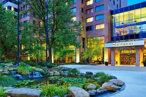 A Sheraton hotel with a landscaped garden featuring a pond and rocks.