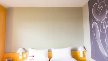Une chambre d’hôtel avec deux lits, une œuvre d’art murale et une table de chevet avec une lampe.