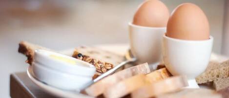 A breakfast plate with eggs, bread, and a bowl of cereal.