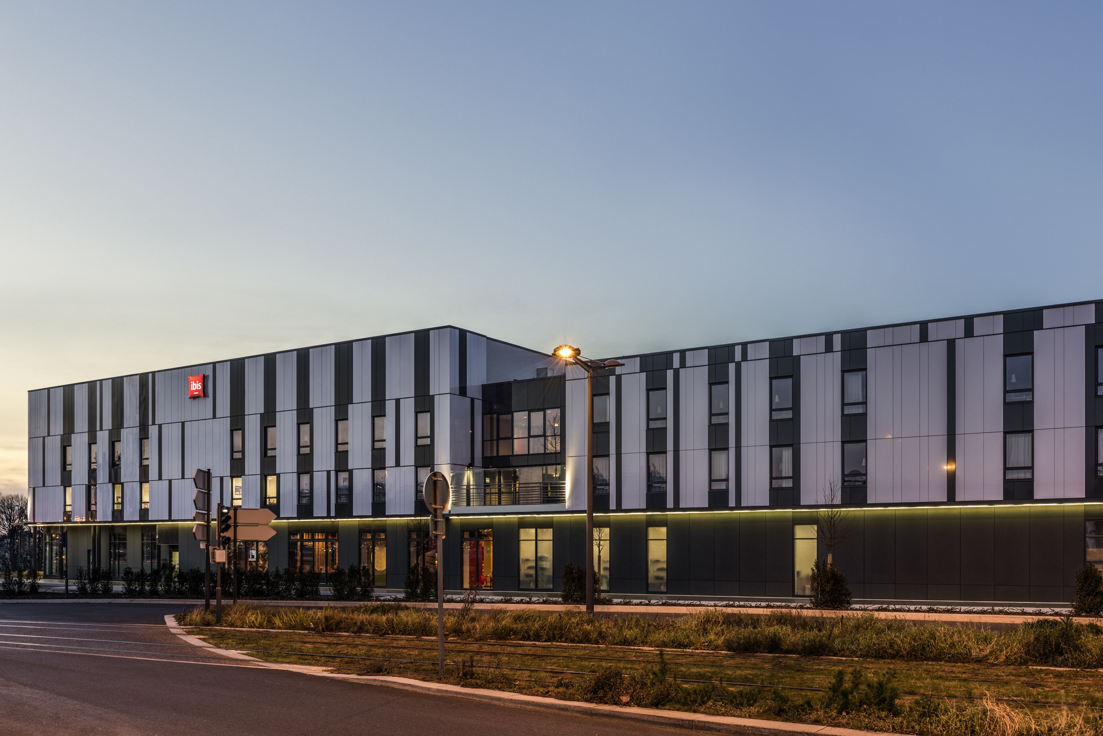 A modern hotel with a flat roof, large windows, and a well-lit facade.