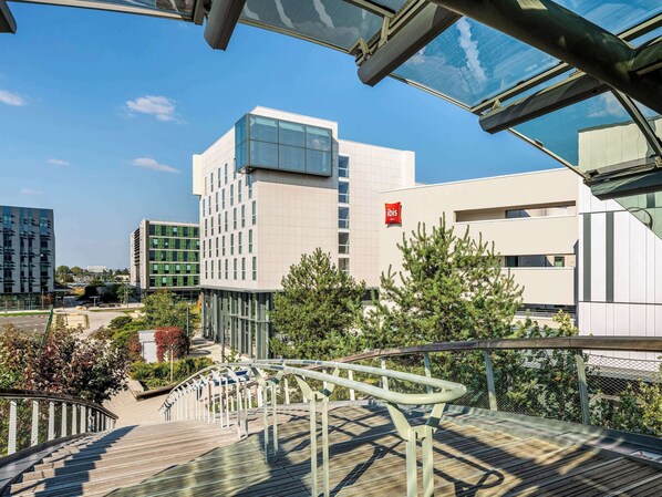 Experience the sleek, contemporary design of this hotel, featuring a glass facade and outdoor deck with metal railing.