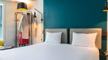 A hotel room with a large bed, two bedside tables, a wardrobe, and a suitcase.