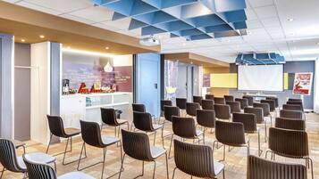A conference room with rows of chairs, a projection screen, and a reception area with a counter and decorative items.