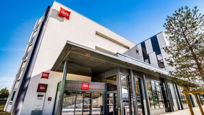 Une entrée d’hôtel moderne avec des portes en verre et un ciel dégagé.