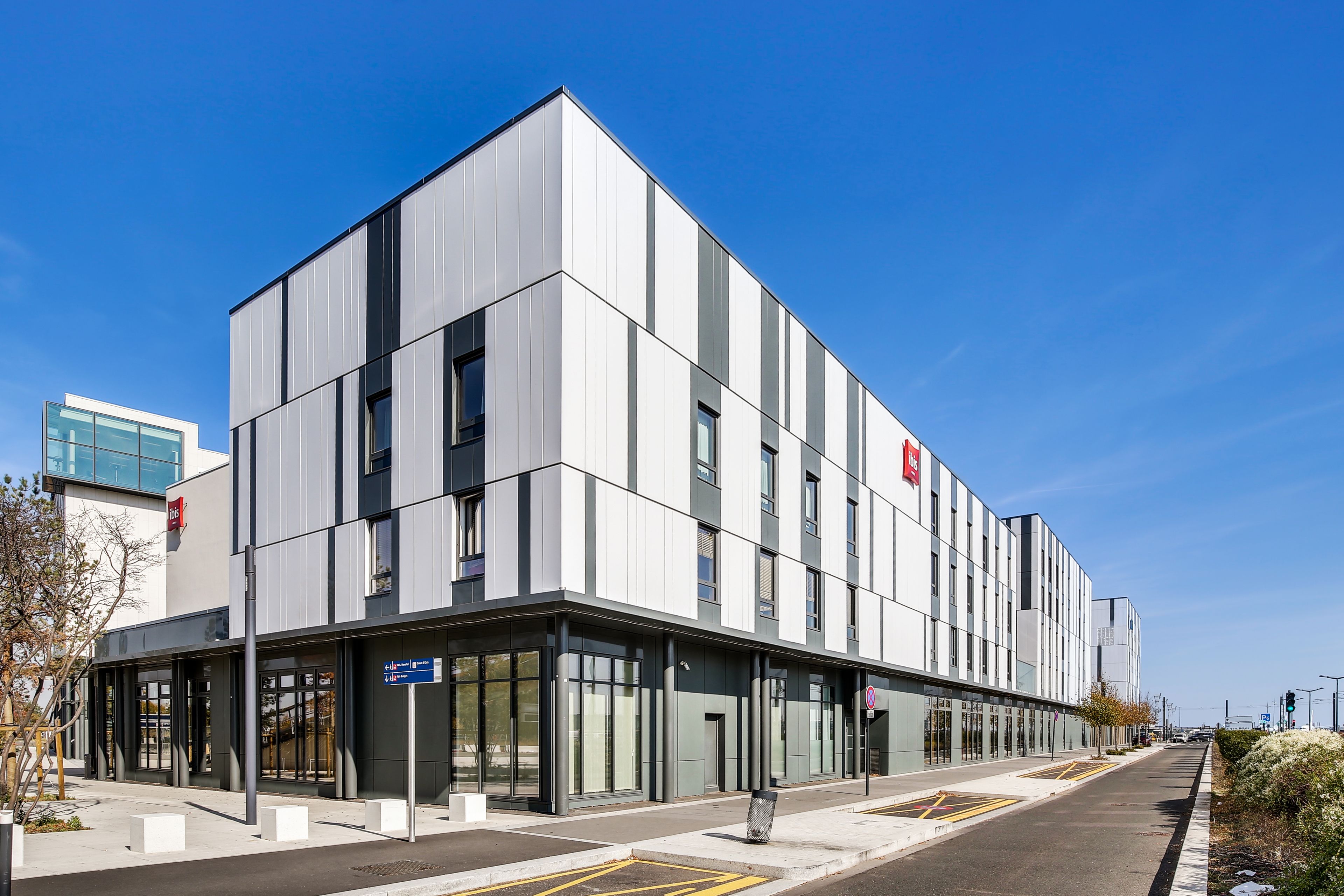 A modern building with a flat facade, large windows, and a clear sky.