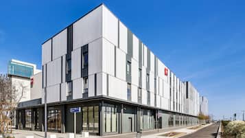 Een modern gebouw met een platte gevel, grote ramen en een heldere lucht.