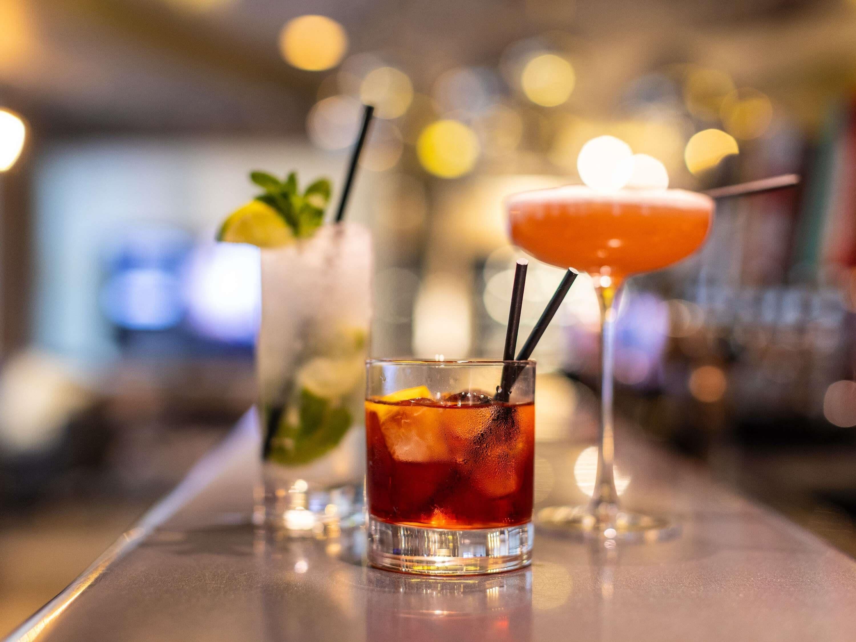 Two cocktails on a bar counter with a blurred background.