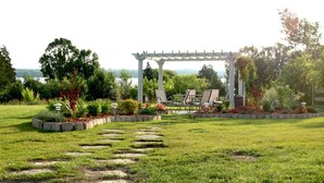 Un jardin agrémenté d’une pergola, d’un espace salon extérieur et d’un chemin en pierre.