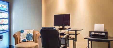 A room with a beige sofa, a black office chair, a desk with a computer, and a printer.