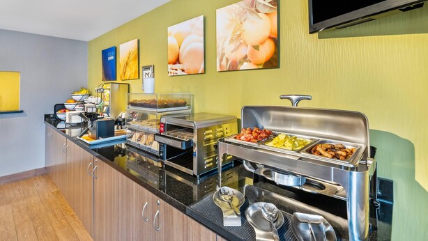 Un buffet proposant une variété de plats et d’ustensiles, un téléviseur fixé au mur et des œuvres d’art accrochées au mur.