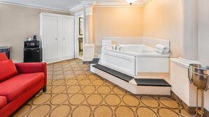 Une chambre d’hôtel avec un canapé rouge, une baignoire blanche, un four à micro-ondes et une machine à café.