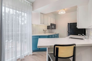 A hotel room with a large bed, a TV, a mirror, and a nightstand. at Sonesta ES Suites Torrance Redondo Beach