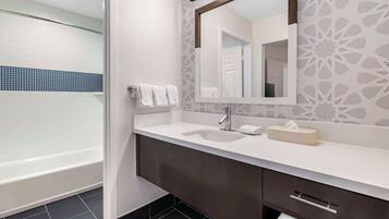 Un baño moderno con un lavamanos blanco, un mueble oscuro y un espejo grande.