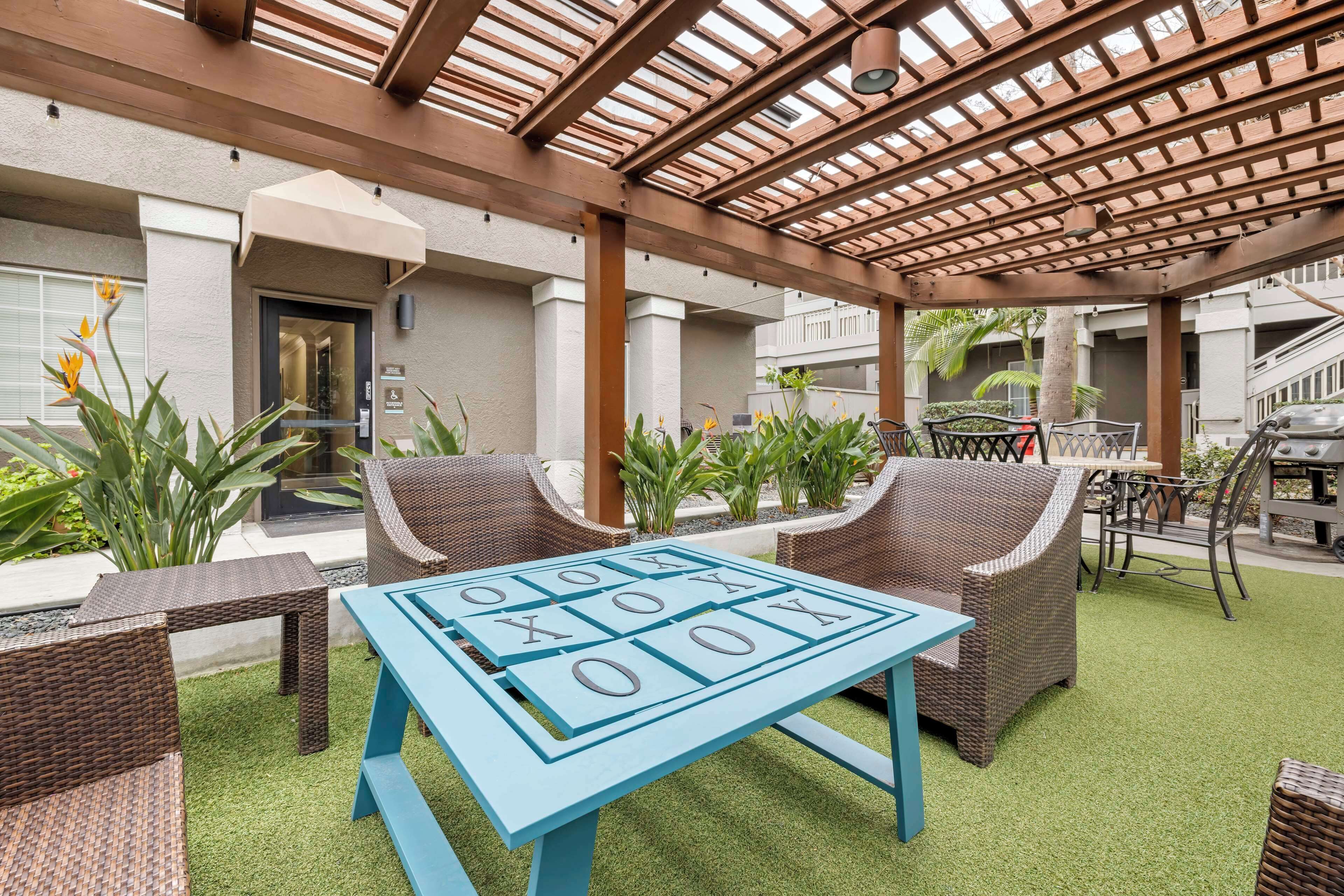 A covered outdoor seating area with wicker furniture and a blue table.