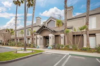 A modern hotel lobby with a seating area, a bar, and large windows offering views of the city. at Sonesta ES Suites Torrance Redondo Beach