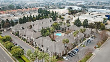 An aerial view of a residential area with multiple buildings, a swimming pool, and a parking lot.
